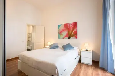 a white bedroom with a bed and a painting on the wall at Minerva 2 Apartment in Rome