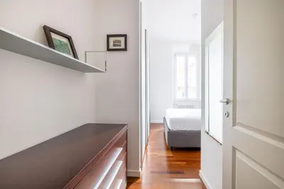 a bedroom with white walls and a wooden dresser at 3BR Comfort Apartment in Rome in Rome