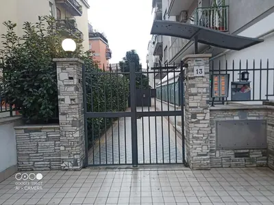 a black iron gate with a stone wall at Domus Gianicolense in Rome