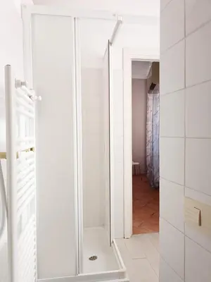 a glass shower door in a white bathroom at Marcello Apartament in Rome