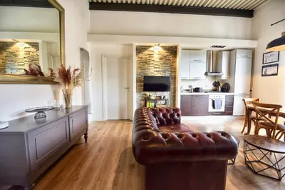 a living room with a leather couch and a kitchen at Industrial Loft Trastevere Station in Rome