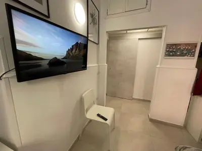 a room with a tv on the wall and a white chair at Pigneto Easy Stay in Rome