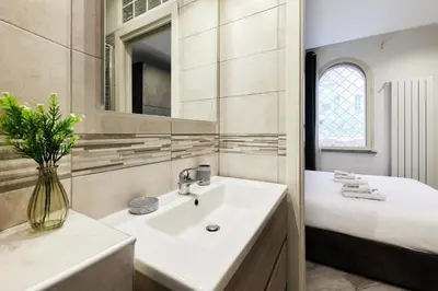 a white bathroom with a sink and a bed at iFlat One step from Colosseum in Rome