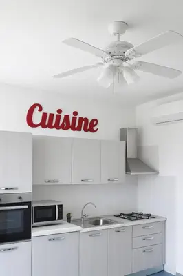 a kitchen with white cabinets and a ceiling fan at Appartamento 