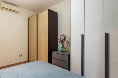 a bedroom with a bed and a cabinet and a vase of flowers at GuestHost - Piazzale delle Provincie Apartment in Rome