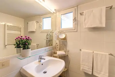 a white bathroom with a sink and a mirror at Amazing penthouse with terrace near Navona Square in Rome