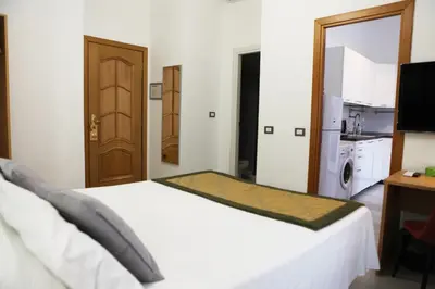 a bedroom with a white bed and a kitchen at Vatican Museum Scipioni BED & Breakfast in Rome