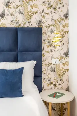 a bed with a blue headboard and a side table at Romi Suite in Rome