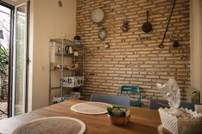 a dining room with a wooden table and a brick wall at TWO-ROOM Apt. under the Aqueduct's ARCH in Pigneto in Rome