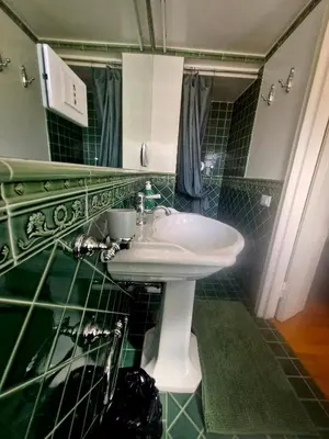 a bathroom with a white sink and green tiles at Apartment luxury Archimede 80 in Rome