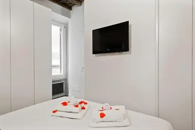 a white room with two white pillows and a tv at HostMe Piazza Navona Apartament in Rome