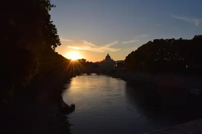 a river with the sun setting in the distance at Boezio43B&B in Rome