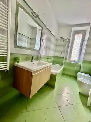 a green bathroom with a sink and a mirror at Angel House - balcony and view in Rome