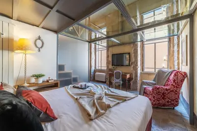 a bedroom with a large bed and a chair at Amazing & Romantic *Loft Testaccio Aventino* in Rome