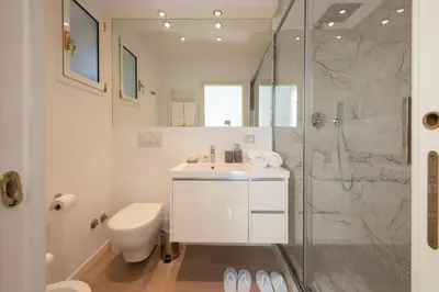 a white bathroom with a sink and a shower at Lucrezio Caro Luxury Apartment in Rome