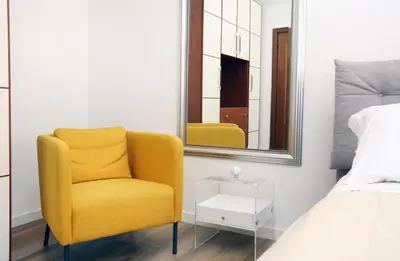 a yellow chair in a bedroom with a mirror at Bibi’s house Vaticano in Rome