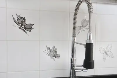 a bathroom sink with a shower faucet with butterflies on the wall at Bibi’s house Vaticano in Rome