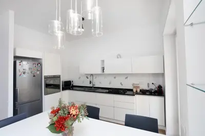 a white kitchen with a table with a vase of flowers at Bibi’s house Vaticano in Rome