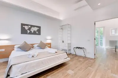 a white bedroom with a large white bed and wooden floors at Beautiful Vatican in Rome