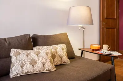a couch with a pillow and a table with a lamp at Trastevering in Rome in Rome