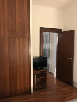 a room with a television and a wooden closet at ALMA Rooms Appia in Rome