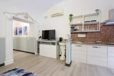 a kitchen with white cabinets and a television in it at Appartamento via di Torre Argentina (Navona) in Rome