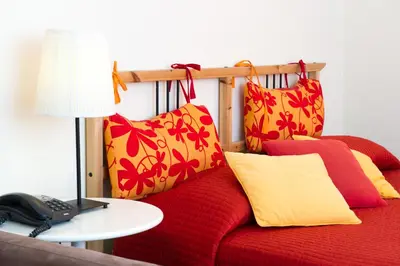 a red couch with red and yellow pillows and a telephone at Boezio House in Rome
