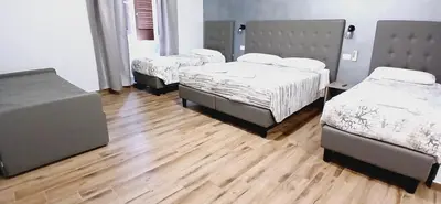 a room with three beds and a wooden floor at ANGI HOME in Rome