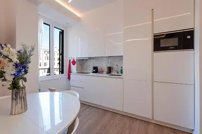a white kitchen with a table and a vase of flowers at Dolce casa al Vaticano in Rome