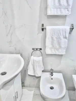 a white bathroom with a sink and a toilet and towels at Domus Euclide in Rome