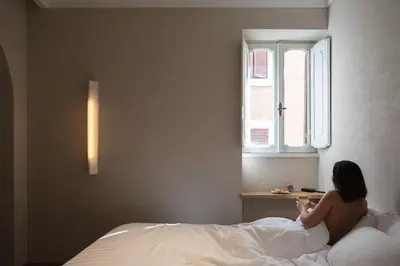 a woman sitting on a bed under a window at P10 DESIGN in Rome