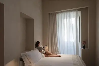 a woman laying on a bed reading a book at P10 DESIGN in Rome