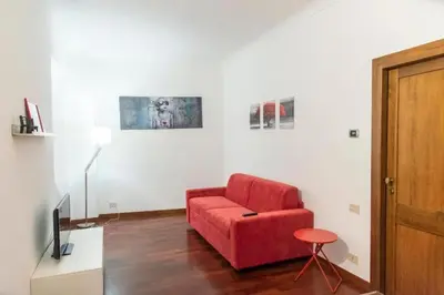 a living room with a red chair and a tv at Welcome to the ColosseHome in Rome