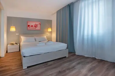 a bedroom with a white bed and a pink painting at COLOSSEUM VIEW ACCOMODATION in Rome
