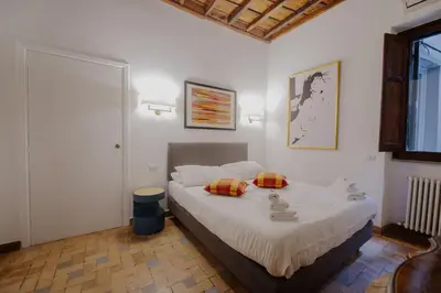 a bedroom with a bed with white sheets and pillows at Via Giulia Charming Apartment with Balcony in Rome