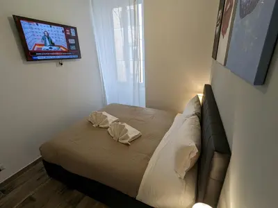 a small bedroom with a bed and a tv on the wall at Borgo Place in Rome