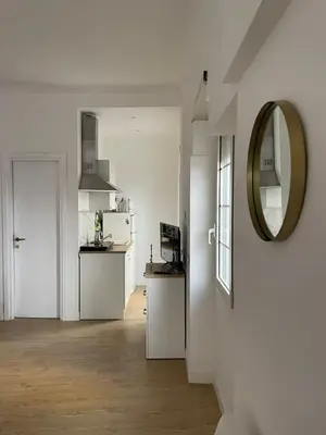 a white room with a mirror and a kitchen at ALMA - Vatican Apartment in Rome