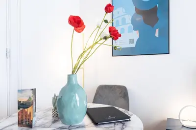 a table with a blue vase with flowers and a laptop at Spanish Steps Exclusive Apartment in Rome