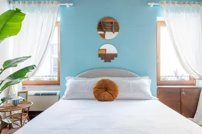 a bedroom with a white bed with a blue wall at Suite Trevi - Charming Loft Near Trevi Fountain in Rome