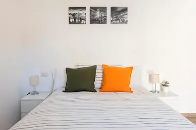 a bed with orange and green pillows on it at central comfortable studio apartment in Rome
