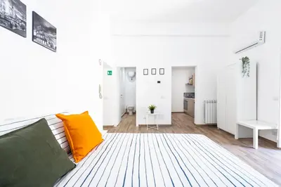 a white living room with a couch and orange pillows at central comfortable studio apartment in Rome