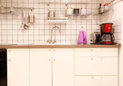 a kitchen with white cabinets and a white tiled wall at Opera House in Rome