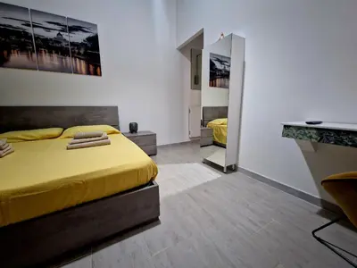 a bedroom with a yellow bed and a mirror at Tiburtina Keys - Roma in Rome