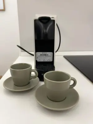 two coffee cups and a phone on a table at flaTminio modern & nice apartment in Rome