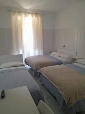 a hotel room with three beds and a window at AltaDomus Roma in Rome