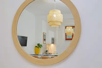 a round mirror on a white wall with a bathroom at Vatican apartment with parking in Rome