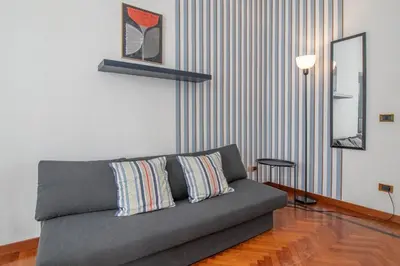 a living room with a gray couch and a mirror at Ezio House in Rome