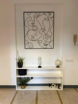 a white shelf with plants on a wall with a picture at Maison San Lorenzo Roma in Rome