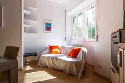 a white room with a couch with two orange pillows at Leoncavallo Retreat in Rome
