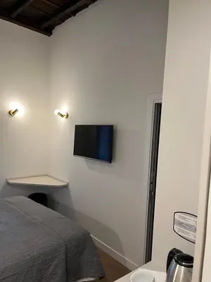a bedroom with a bed and a tv on the wall at Maison Romana Trastevere Suites in Rome